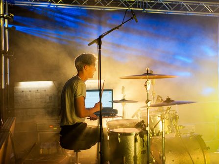 Schlagzeuger auf der Bühne im Nebel und Scheinwerferlicht