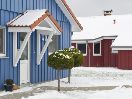 Das Bild zeigt den Eingang eines der blauen Ferienhäuser im Ferienpark Südsee oder (Neu-)Seeland im Schnee.