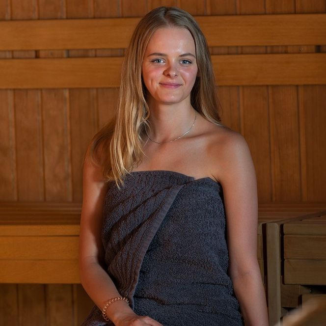 Frau sitzt in der Tennensauna und schaut in die Kamera