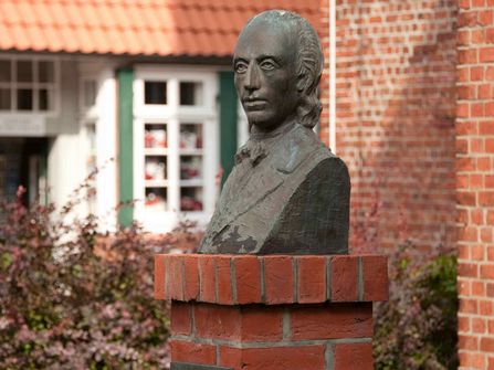 Büste Johann Heinrich Voß mit Johann-Heinrich-Voß Literaturmuseum im Hintergrund