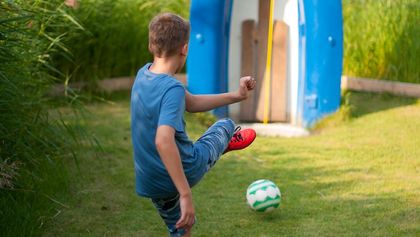 Ein Junge schießt den Fußball in das Ziel an einer Station beim Fußballgolf