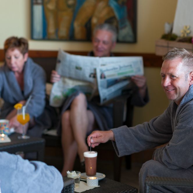 Otterndorf Bistro der Saunalandschaft - Drei Gäste am Tisch, ein weiter Gast liest im Hintergrund Zeitung