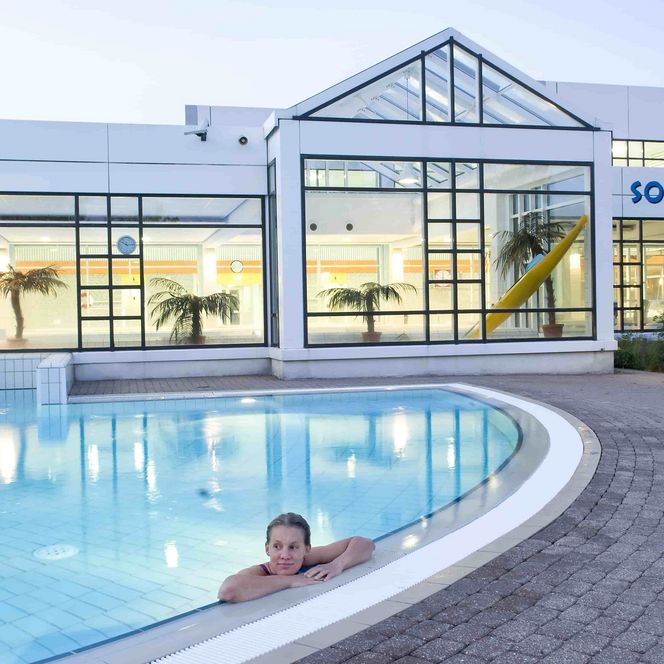 Sole-Therme Otterndor bei Tag mit einer Frau im Wasser am Beckenrand und Blick auf das Schwimmbad