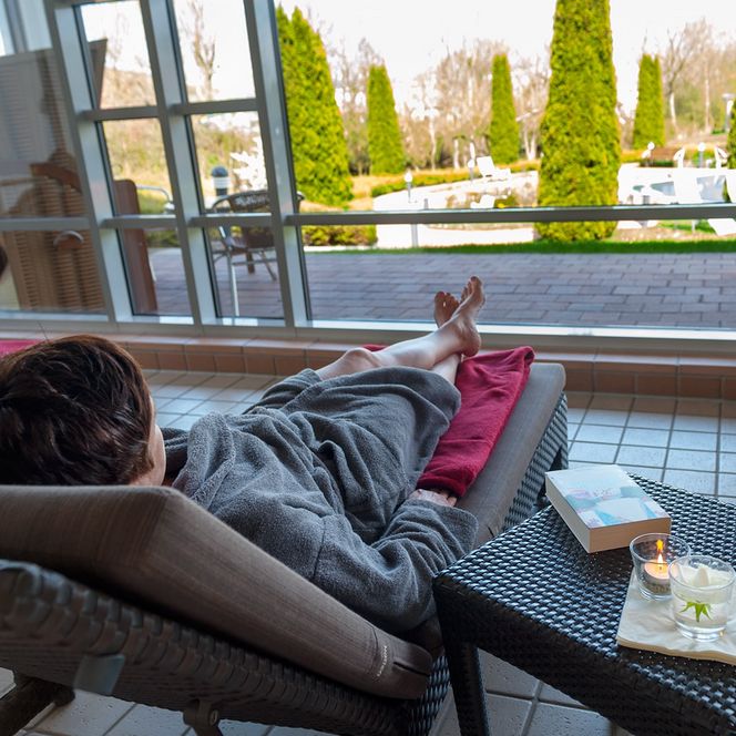 Frau liegt im Ruhebereich der Sole-Therme Otterndorf mit Blick auf den Außenbereich