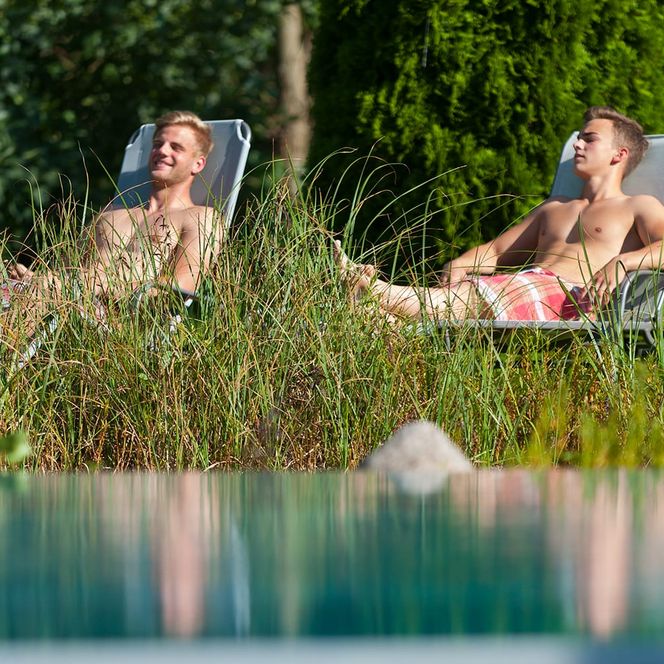 Saunalanschaft Außenbereich Sonnenliegen mit 2 Männern bei Sonnenschein