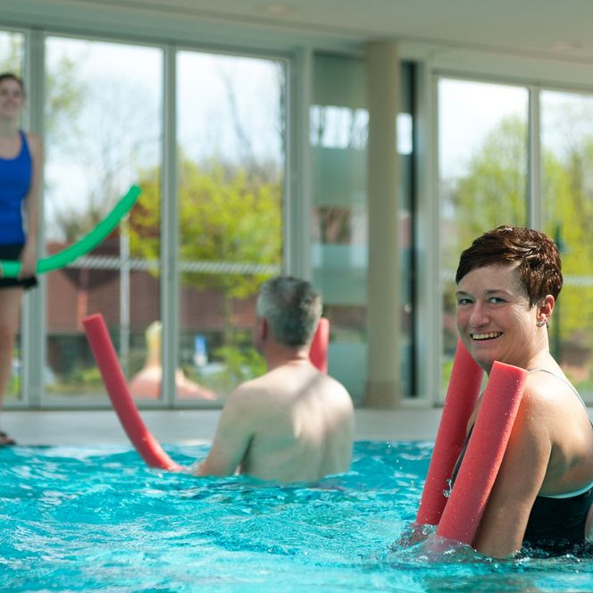 Aquafitness mit Mann und Frau und Schwimmnudeln