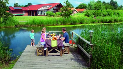 Familie frühstückt auf Bank am See