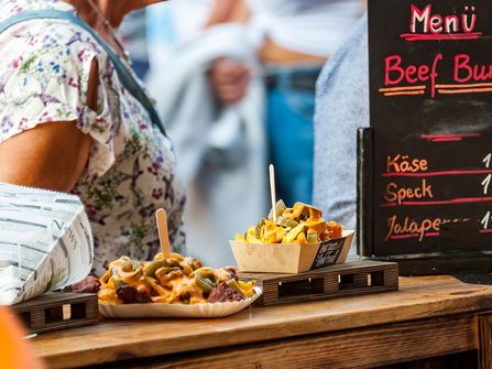 Pommes mit Käse, Speck und Jalapenos an einer Imbissbude auf dem Altstadtfest