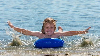 Junge badet mit Luftmatratze in der Nordsee